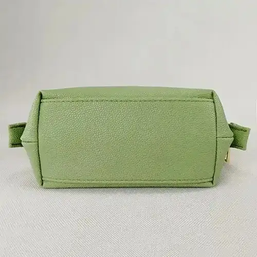 Close-up of premium pebbled vegan leather texture and reinforced gold zipper on a custom makeup pouch.